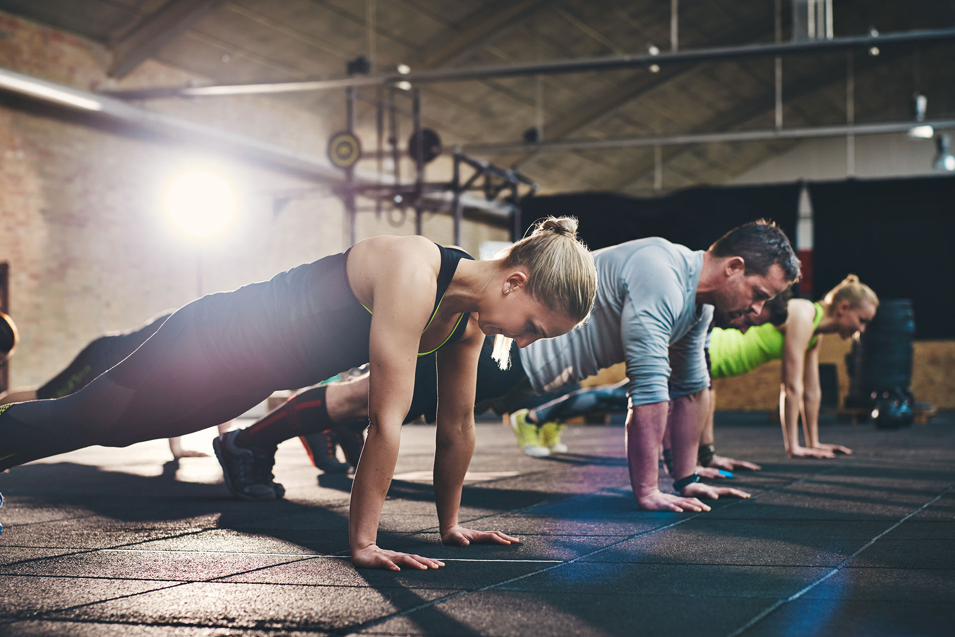 Group fitness class at Mass Appeal Fitness in Winchester, TN with members holding plank positions during a strength and conditioning workout in a 24-hour local gym.