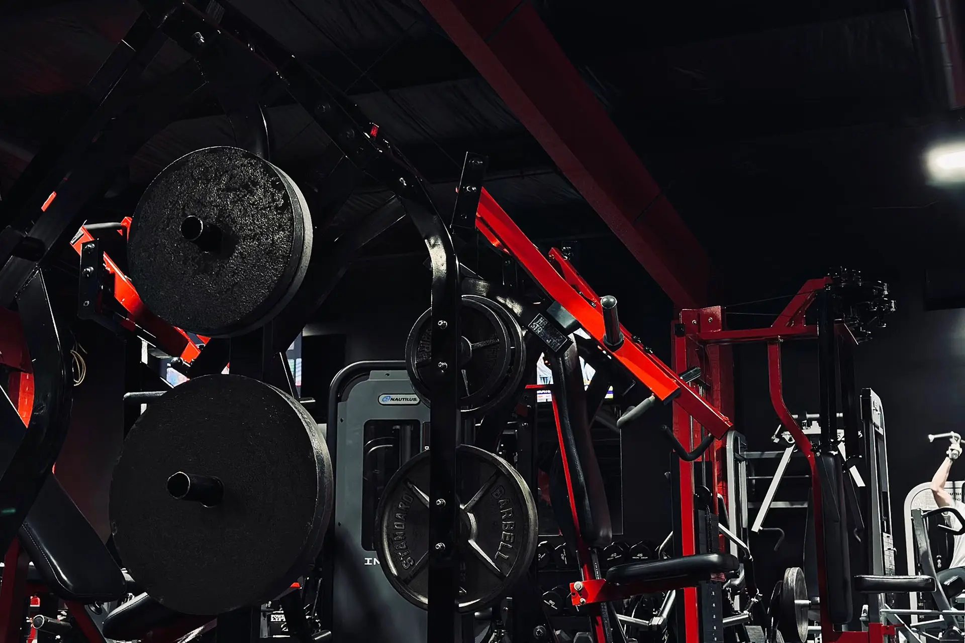 Close-up of strength training equipment and weight plates at Mass Appeal Fitness in Winchester, TN, featuring black and red machines in a 24-hour local gym.